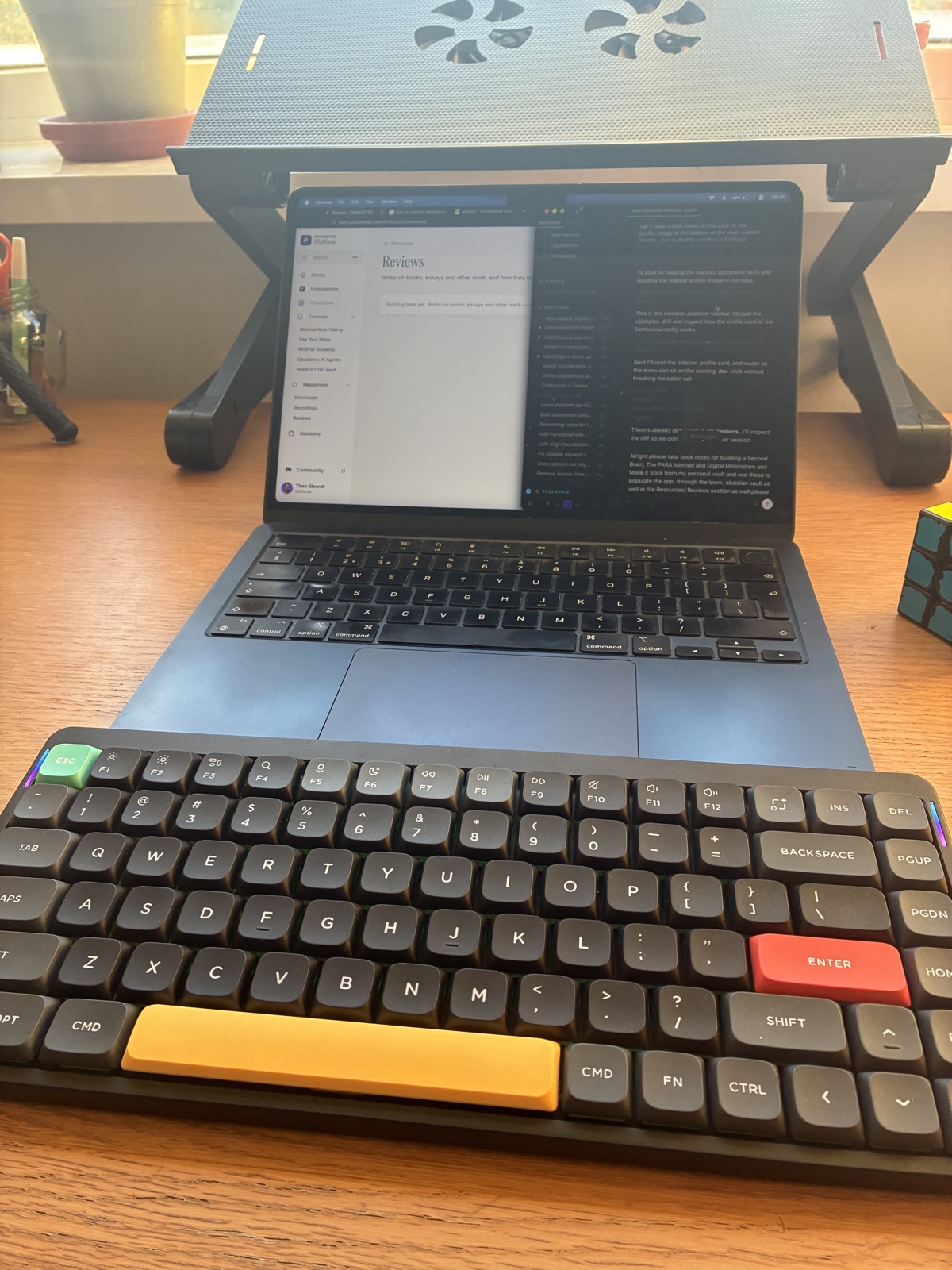 A MacBook on a stand with a mechanical keyboard in the foreground
